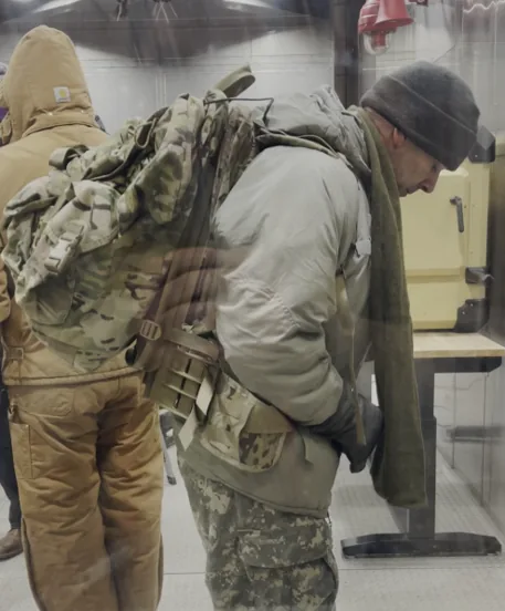 A tester in cold-weather gear shouldering a Lightning Pack inside a cold chamber at the US Army CRREL facility.